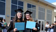 Graduates hold up their diplomas after the 2020 commencement